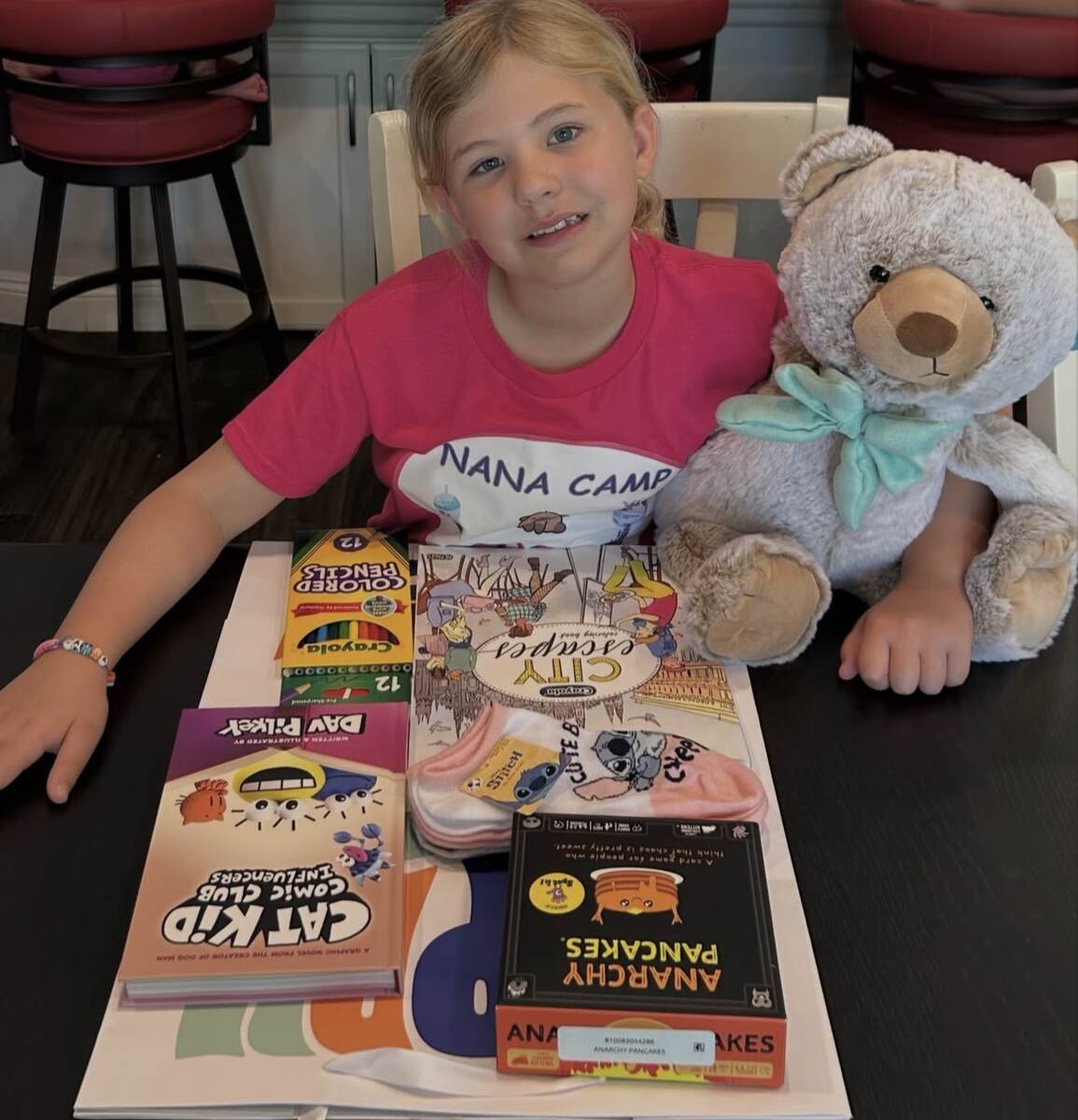 Child smiling with a teddy bear and birthday gifts