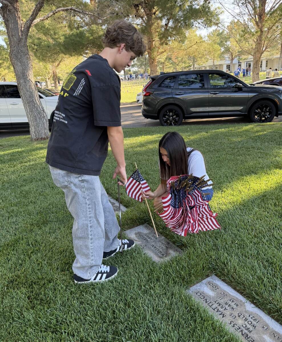 Young volunteers placing American flags beside veterans' memorial markers