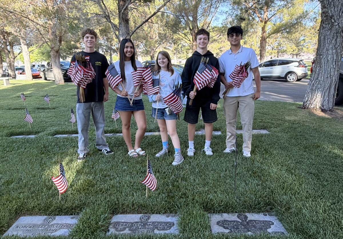 Youth volunteers holding American flags at the Veterans Memorial