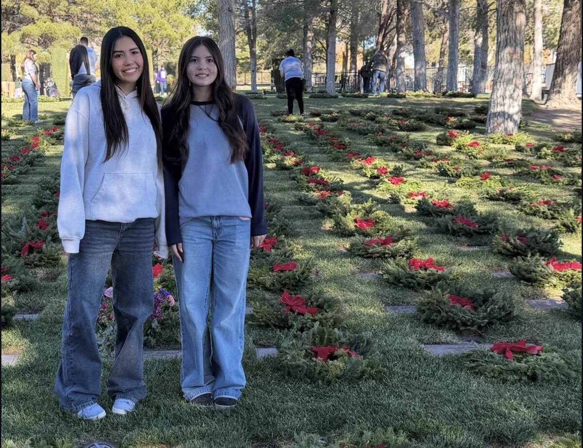 Aiyana and a youth volunteer standing among wreaths placed at veterans' graves